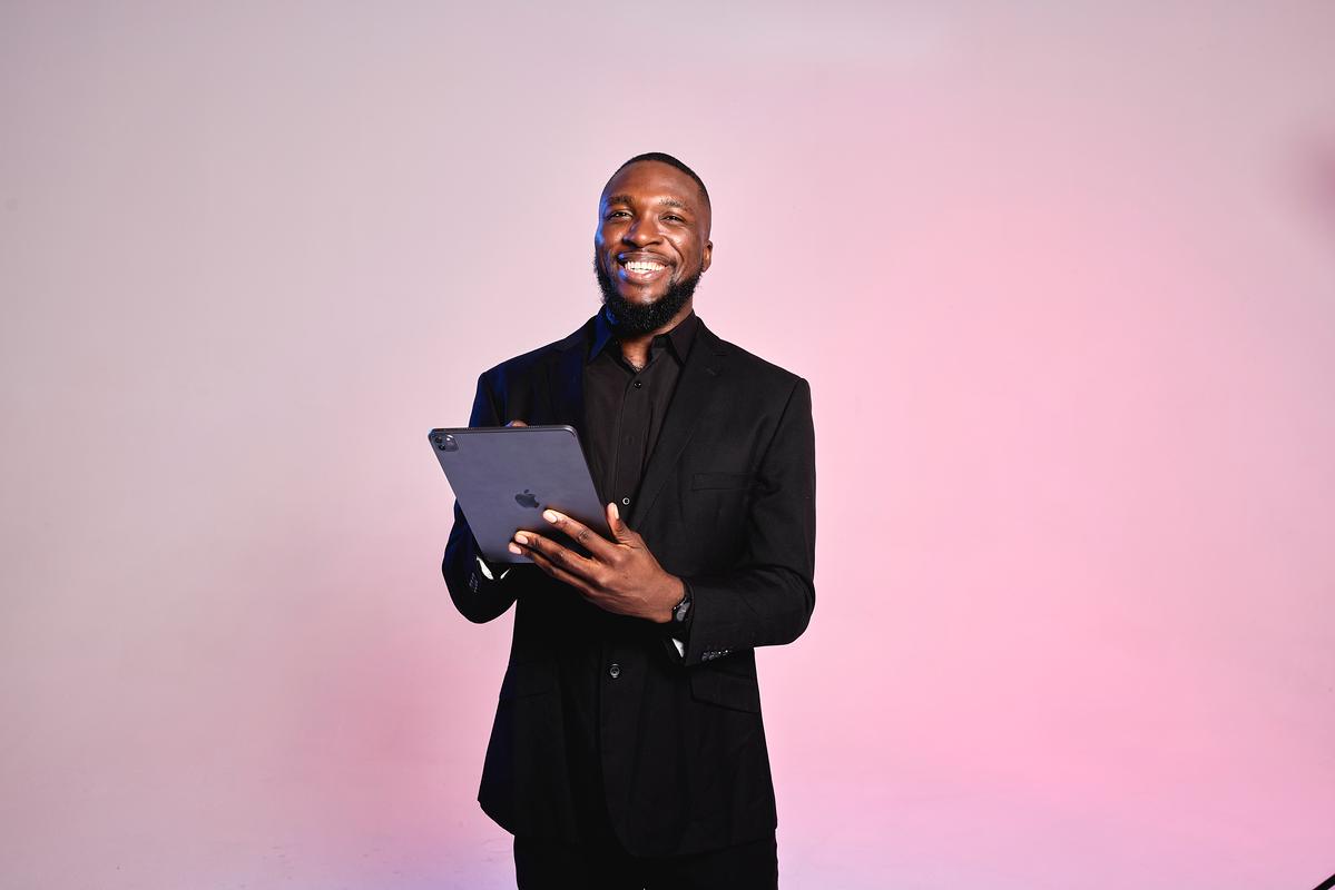 A medspa manager holds a tablet, smiling as he welcomes medspa clients.