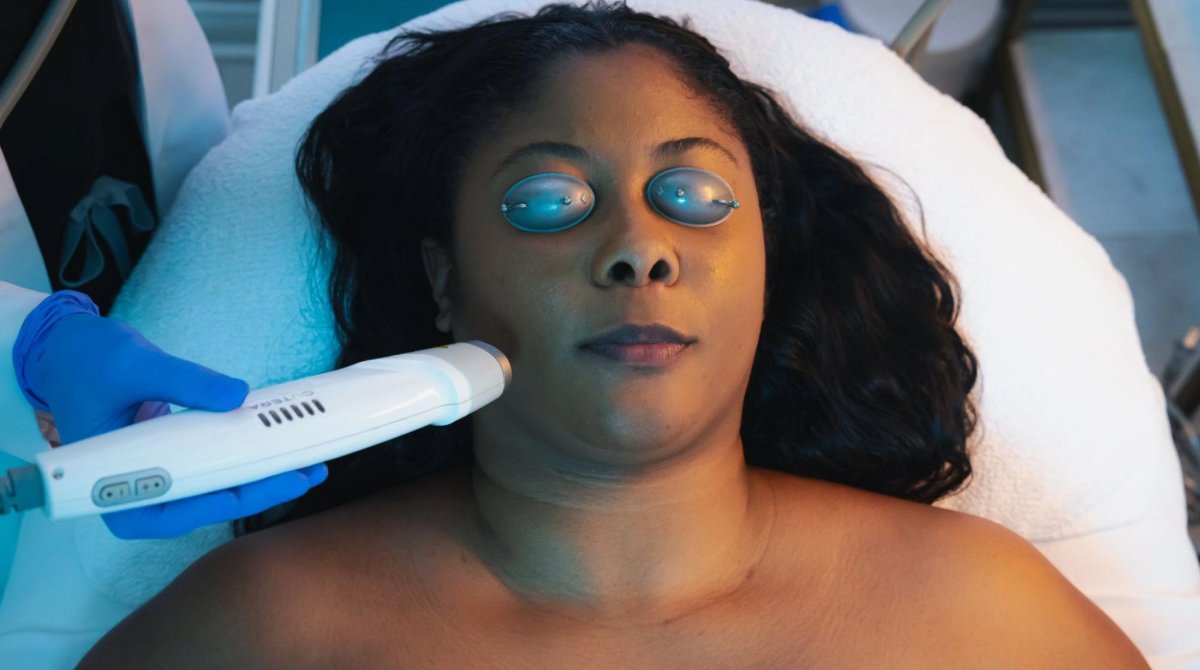 A woman with her eyes closed receives a skin treatment from a specialized tool.