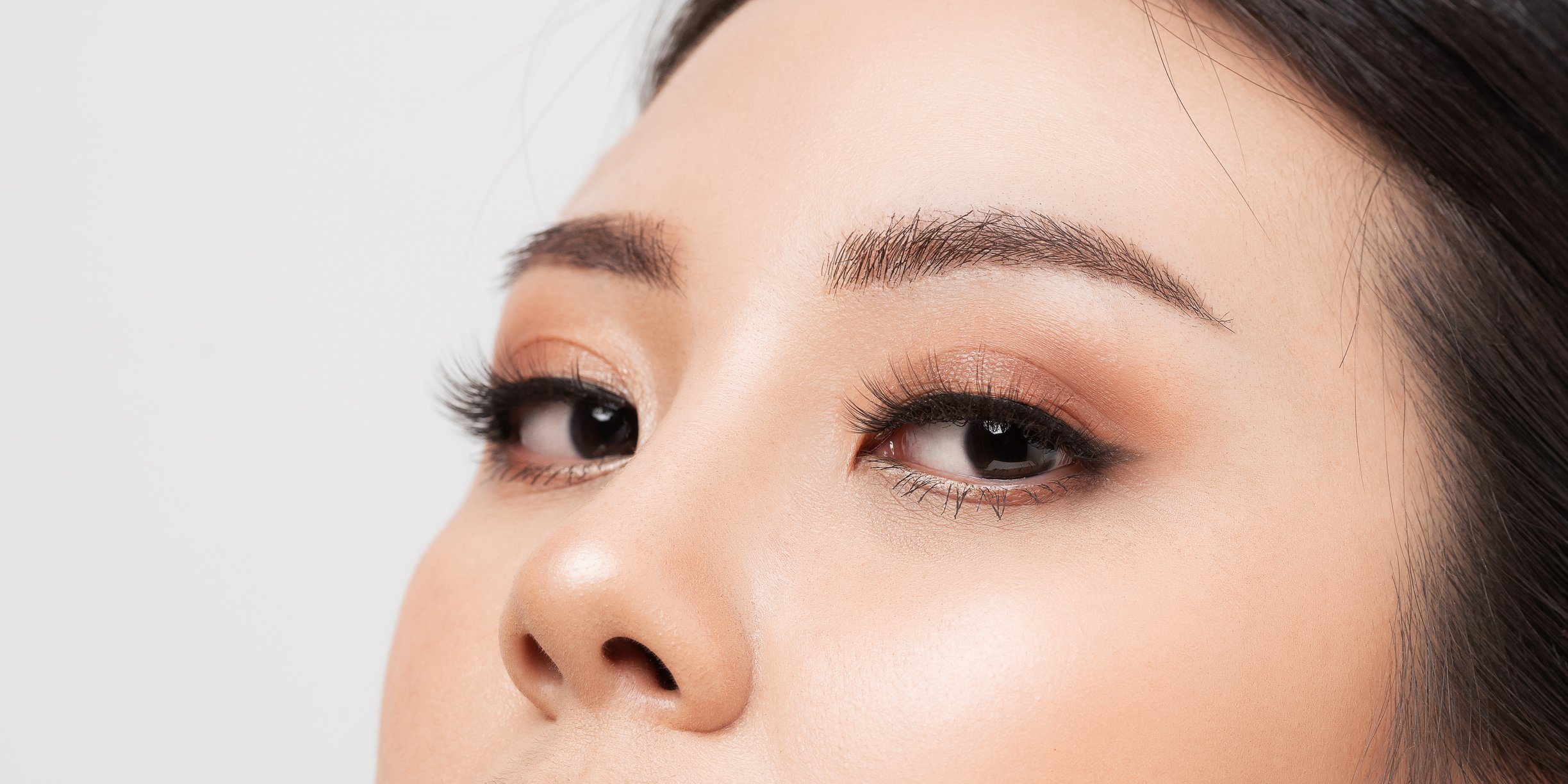 A close-up of a woman's brow area. Her lashes are long and her eyebrows are expertly manicured.