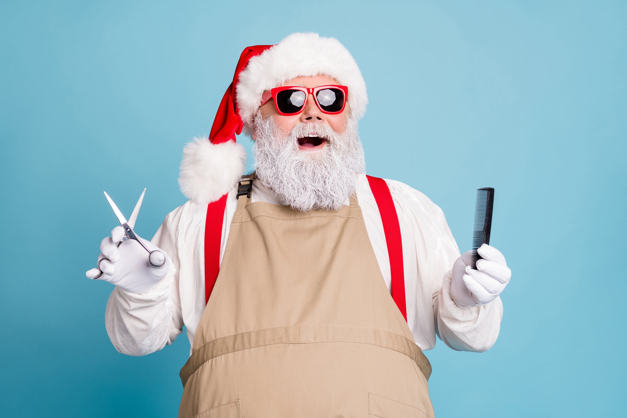 Santa Claus holds a comb and a pair of haircutting scissors with a look of amazement