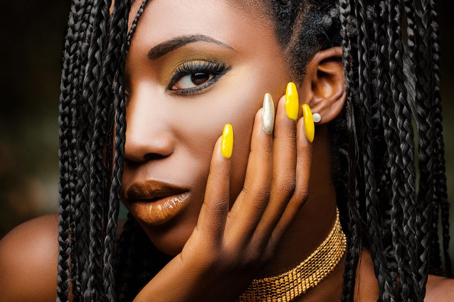 A close-up shot of a young woman showing off glittery gold and silver nails