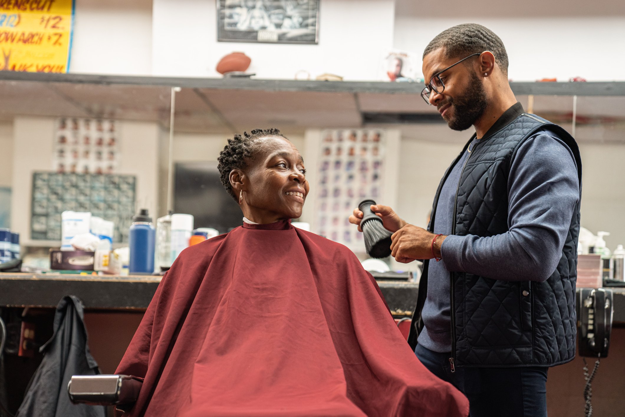 A barber attends to a smiling client.