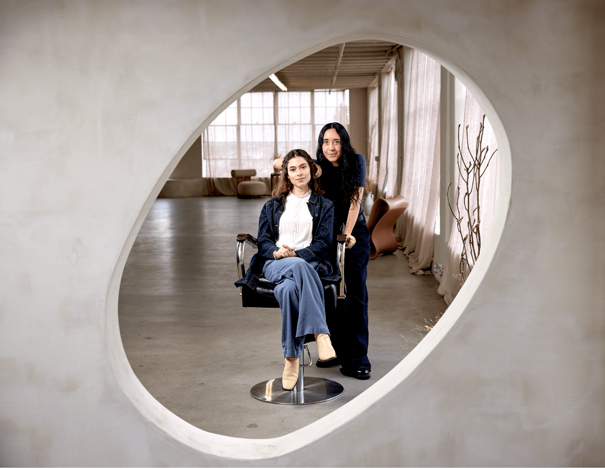 A hair stylist services a customer in her chair while looking into a mirror.