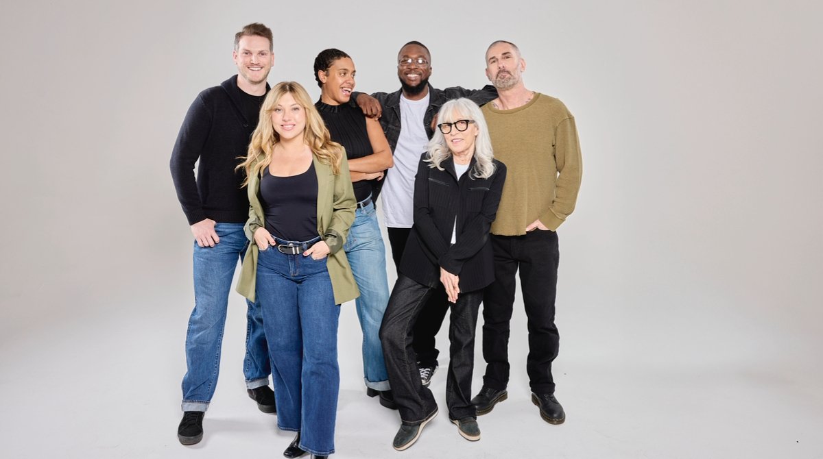 A group of people stand together smiling.