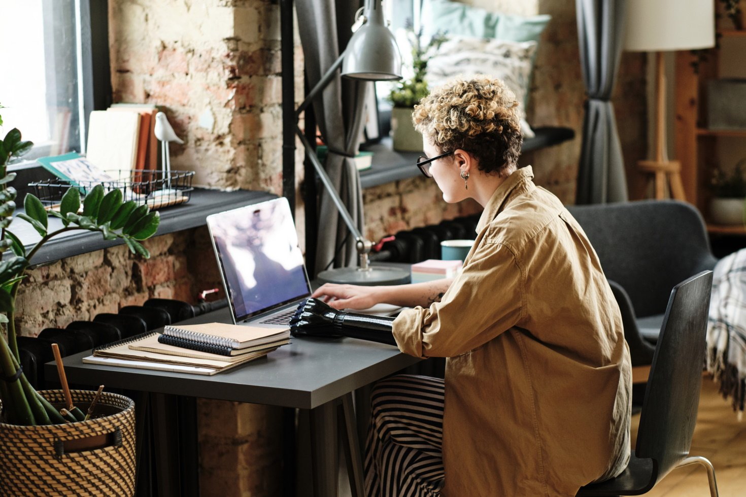 A woman with a bionic arm sits at a desk while using a laptop.
