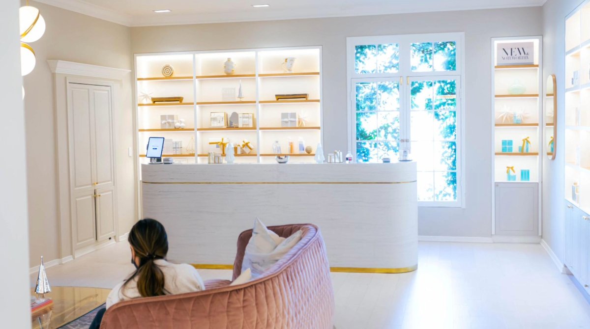 A woman sitting on a sofa in a medspa lobby.