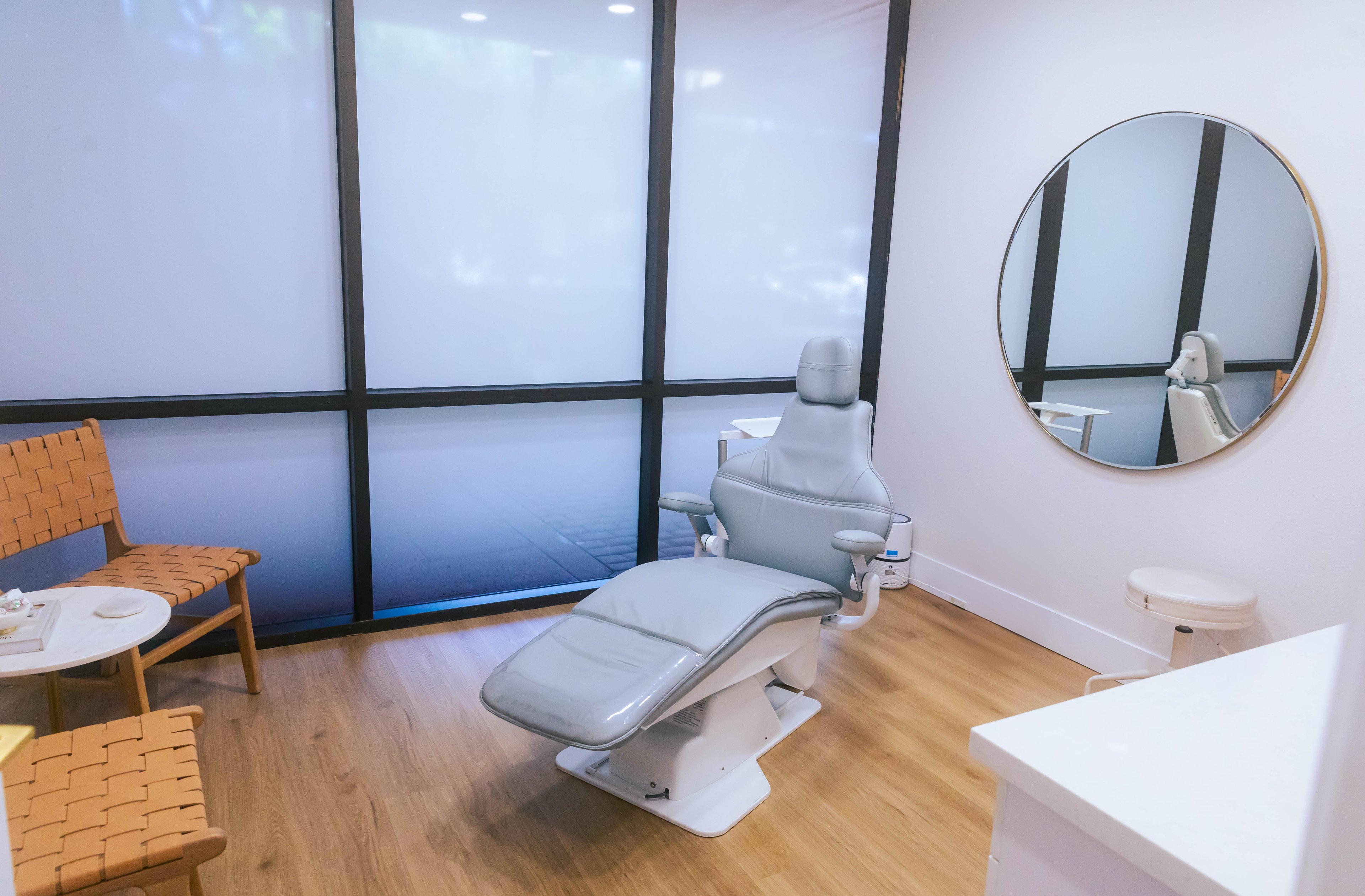 A medspa patient room containing a treatment chair, mirror and chairs.