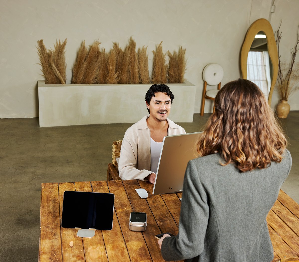 A man checks in a salon client at the reception desk.