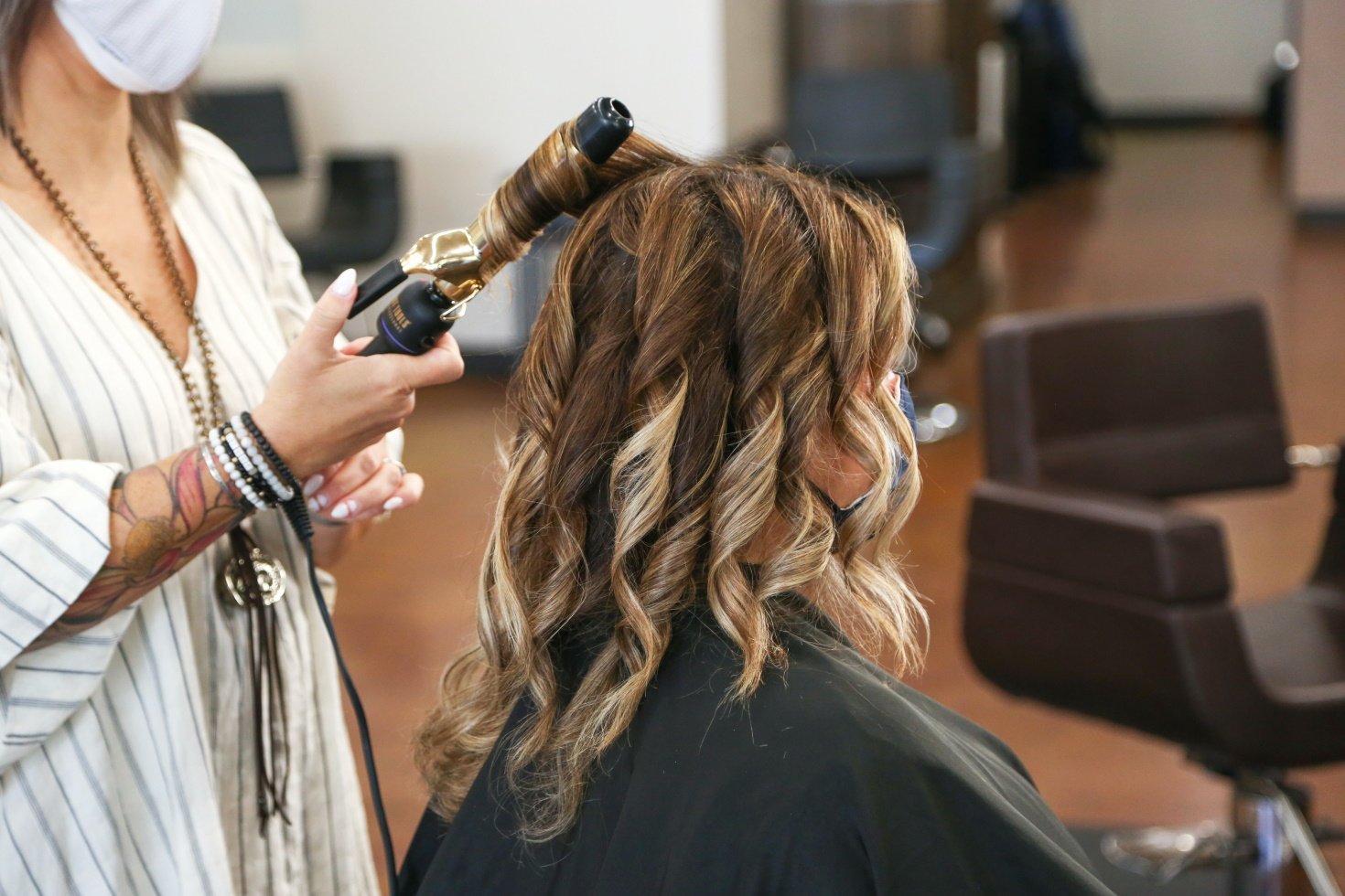 A woman sits in a salon getting her hair curled.