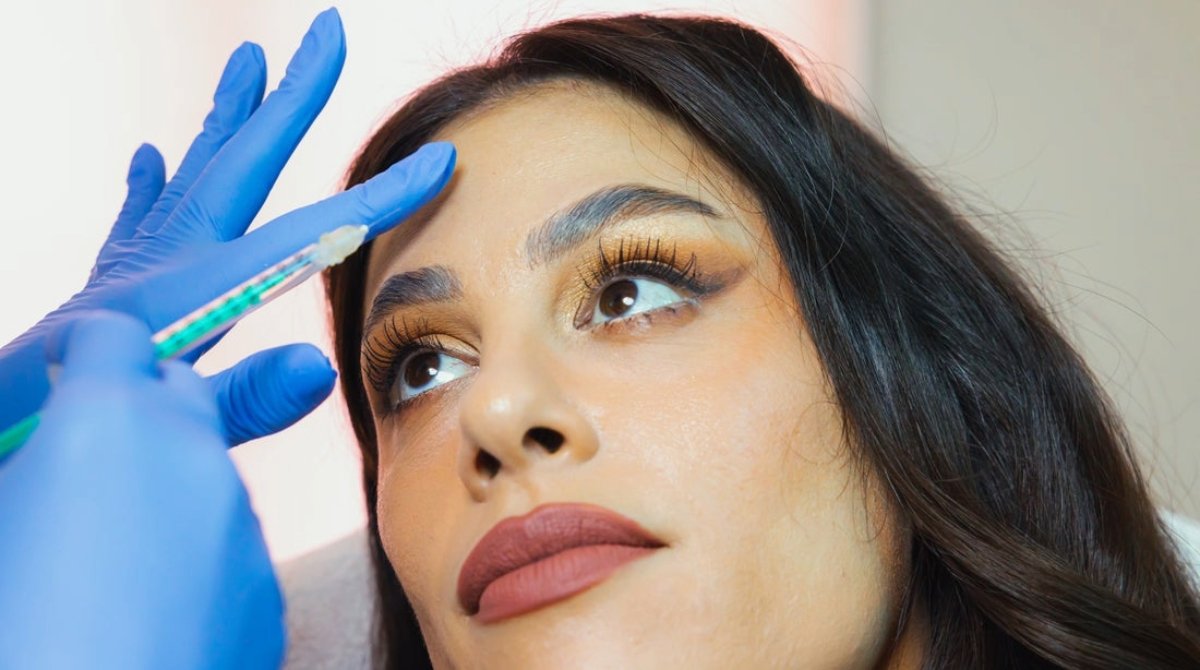 A medspa client prepares to receive a forehead injection