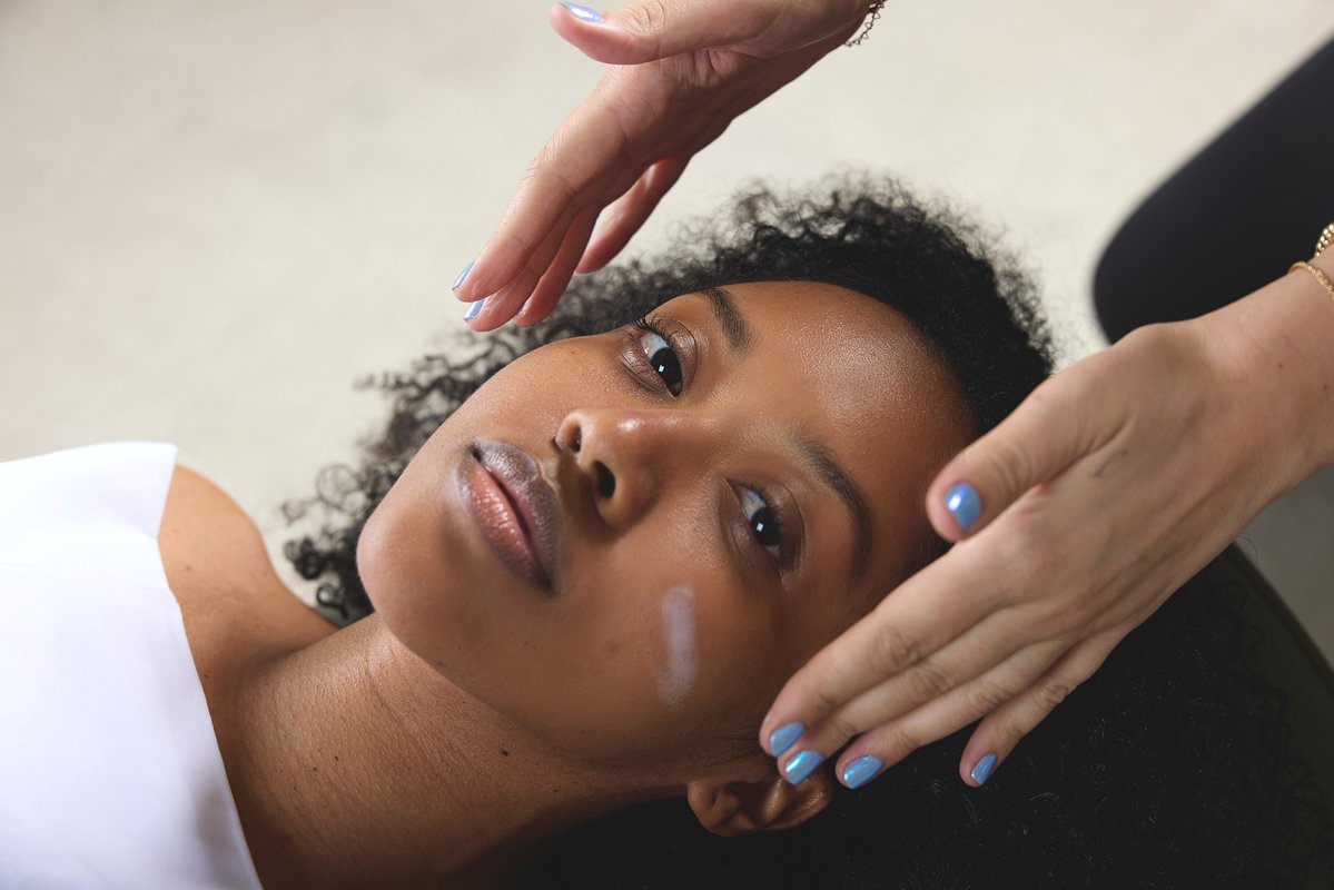 A woman lying down in a medical spa treatment chair receiving a facial.